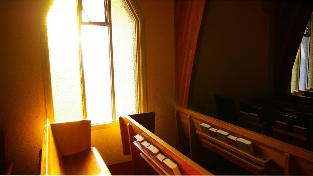 A empty church pew bathed in sunlight. Suggests forgiveness from sin. 